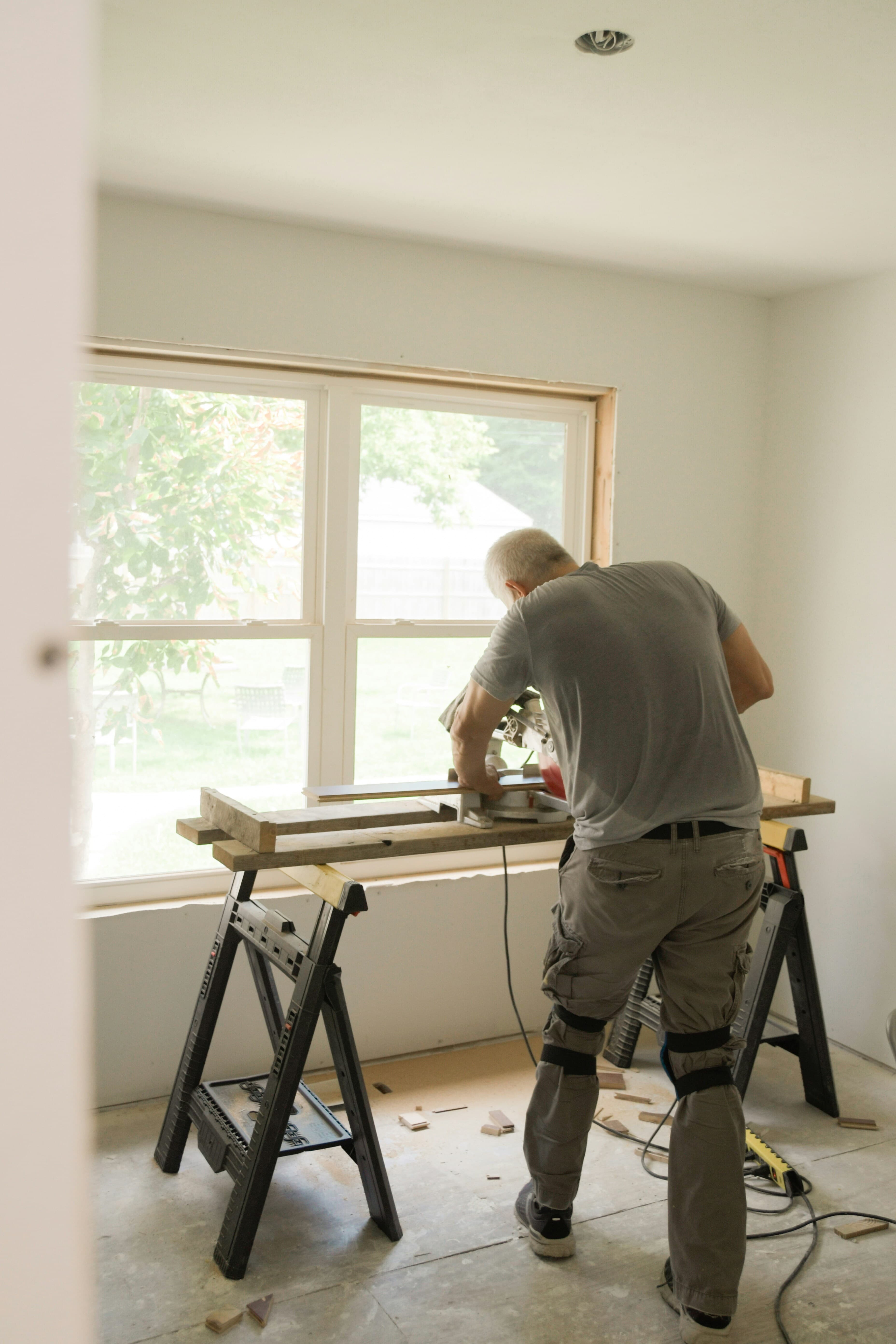 Snickare som kapar list vid ett fönster på en renovering
